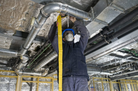 Worker Wrapping An HVAC Air Duct With Foil Tape