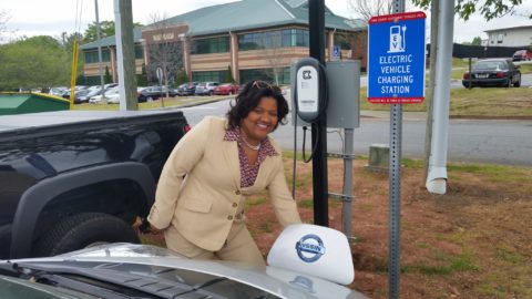Employee Charging Electric Vehicle At Outdoor Charging Station